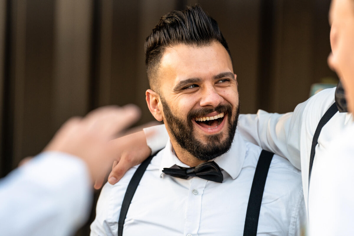 Candid photo of groomsman laughing at a wedding reception in Ashville NC.