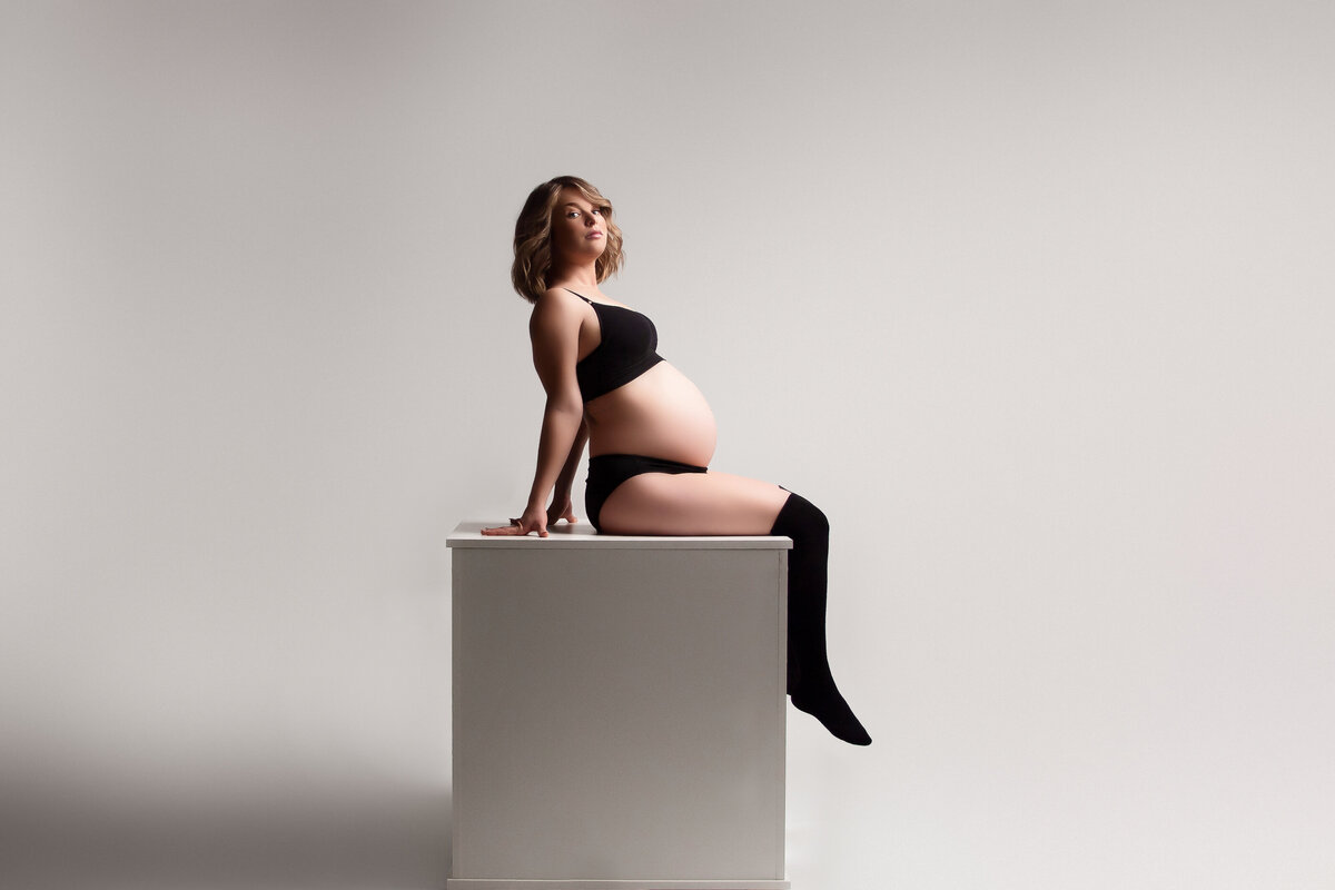 pregnant mom posed on a posing cube in a black bra & underwear