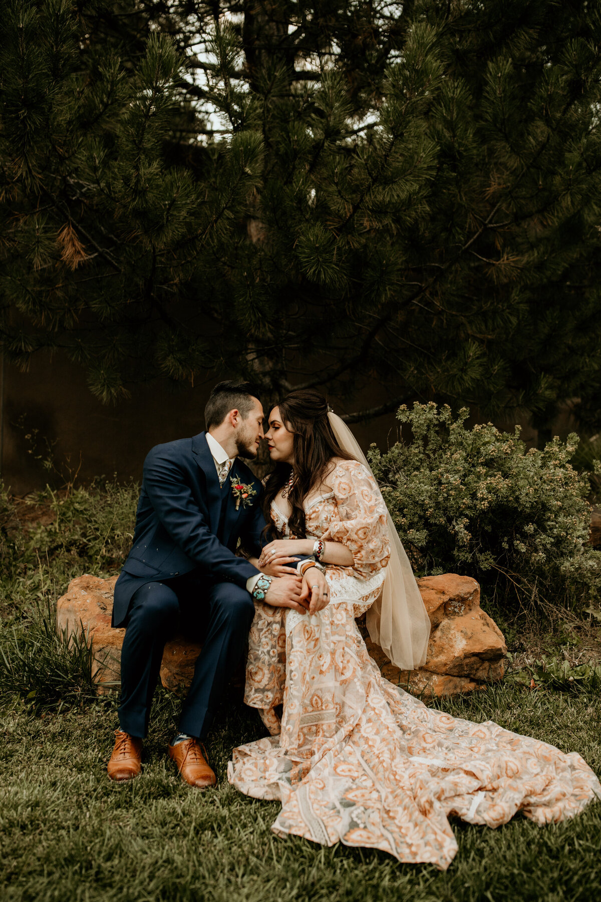 bride and groom sitting together with southwest jewelry  and a long peach wedding gown
