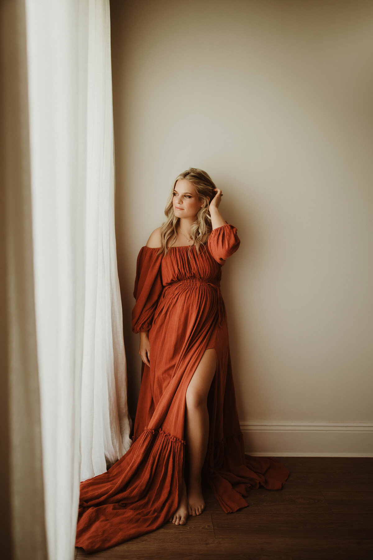 Pregnant woman in long gown holding bump outdoors, Sydney maternity photography.