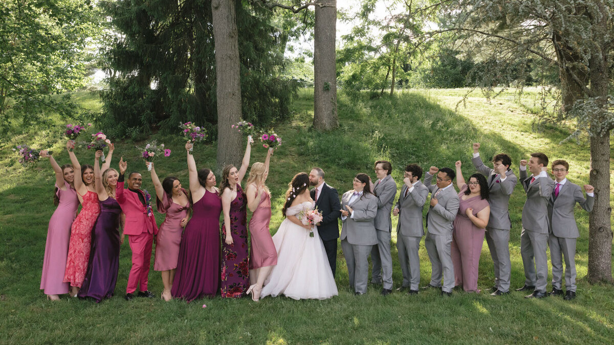 Bride and groom kissing with their entourage cheering