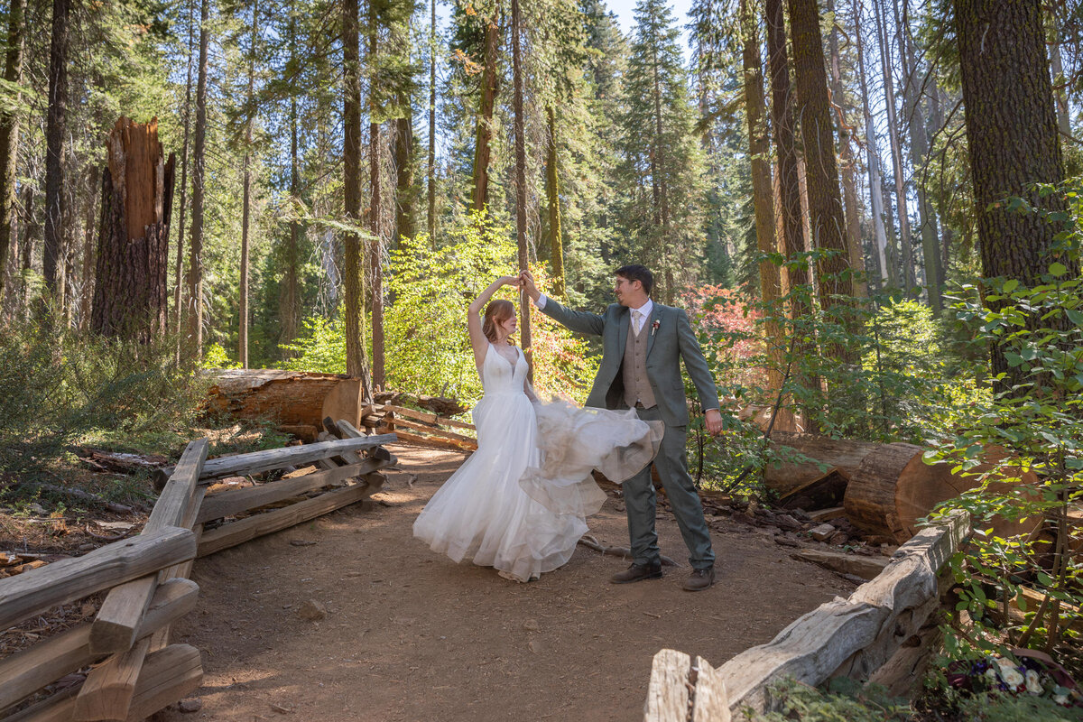 A groom twirls his bride around while they stand in a grove of trees in California on their elopement day.