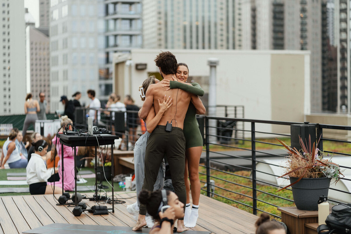 Picture of women hugging a male yoga instructor with his shirt off