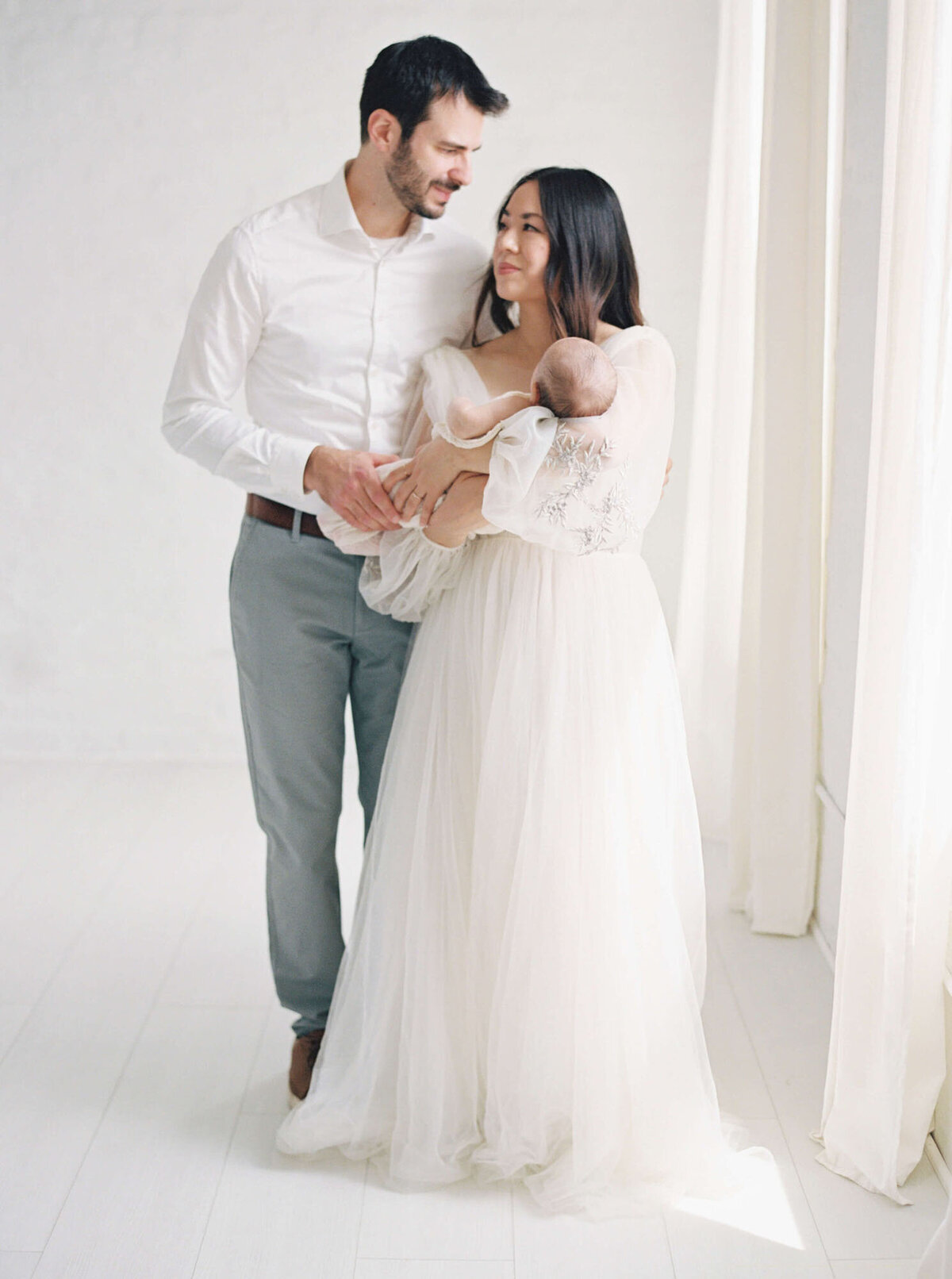 Parents cuddling their newborn during an in-home San Francisco Bay Area newborn photographer session.