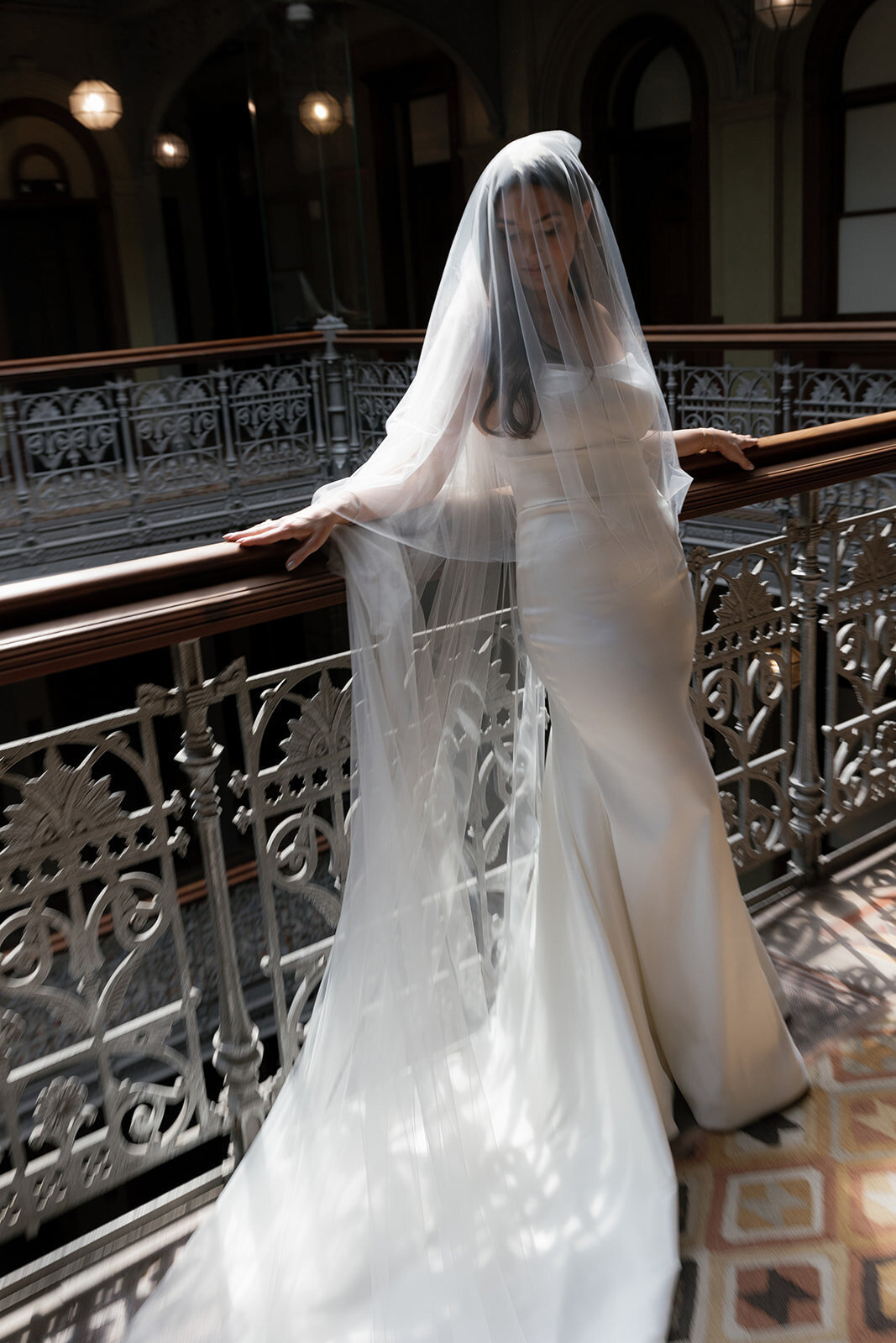Bride posing for photoshoot in a white dress with staircase
