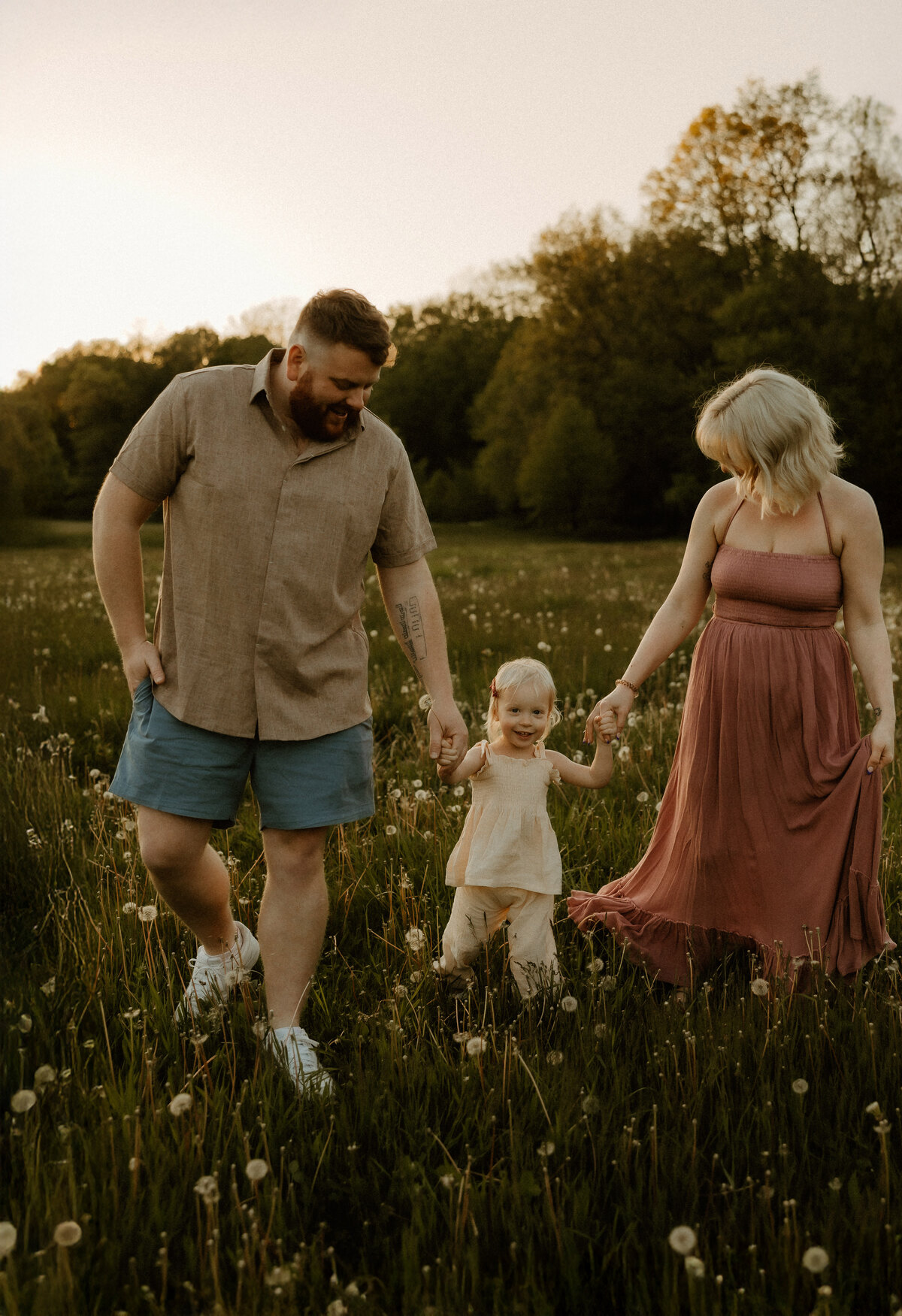 family walks together in field of dandelions in south bend indiana during photo session