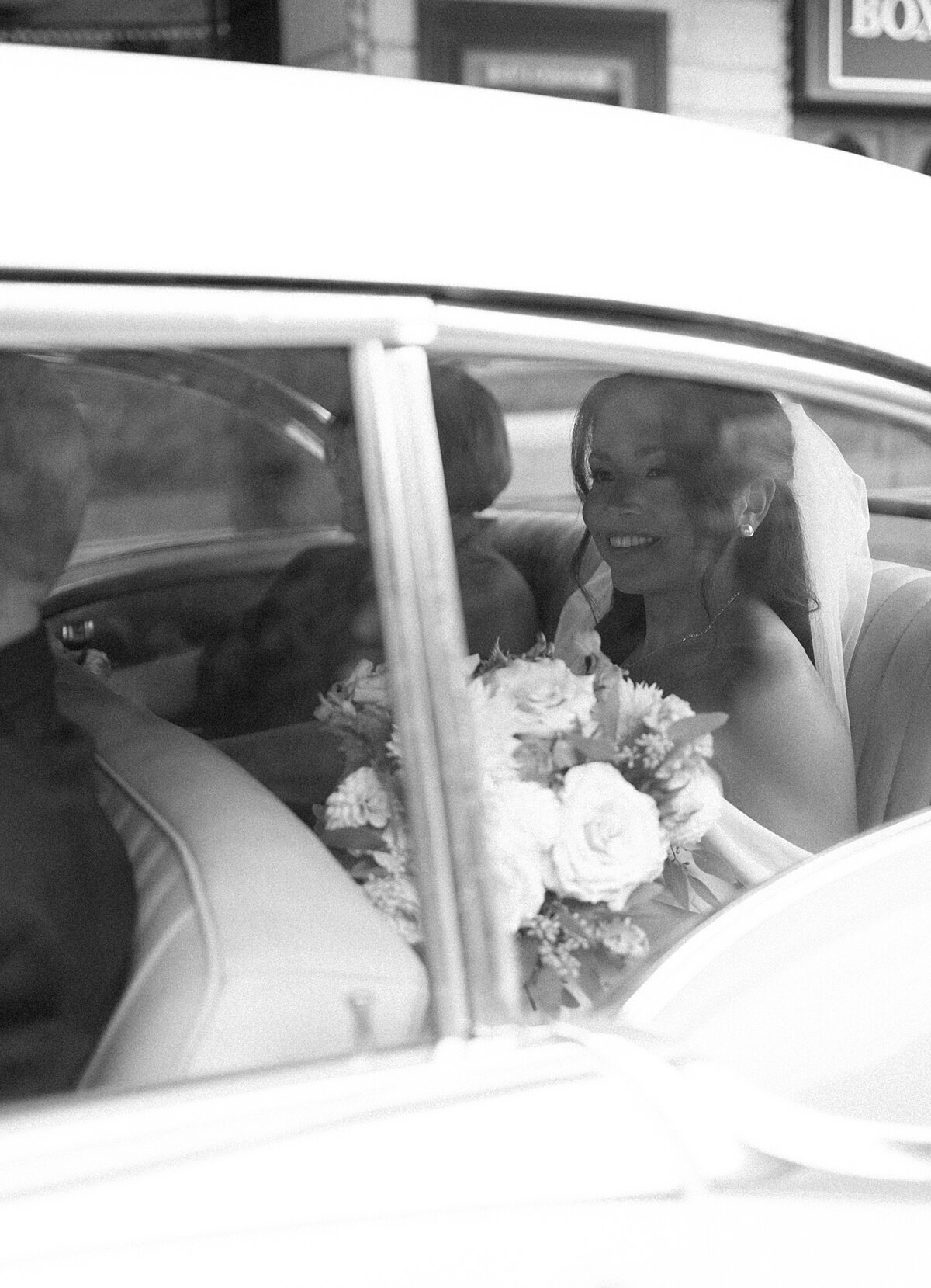 Bride sitting in car waiting for catholic ceremony to begin in a classic gown with her mom nearby. Chicago catholic wedding photographed by Chicago wedding photographer, Allison Francois Photography