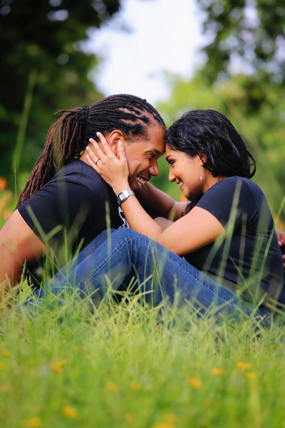 Couple sits together in idyllic field while gazing into each other's eyes. Photo by Ross Photography, Trinidad, W.I..