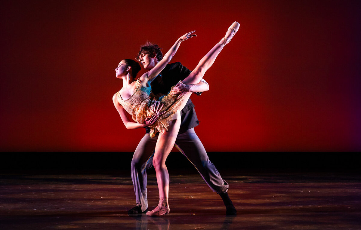 Man and woman dancing together on a stage lit in red