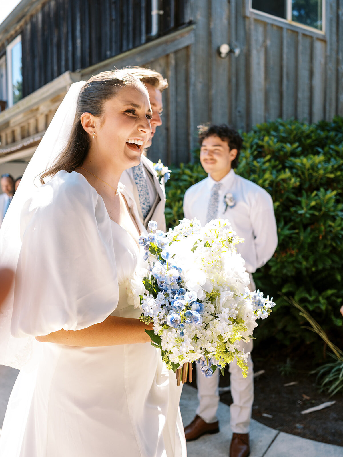 A bride smiling and holding a bouquet of flowers.