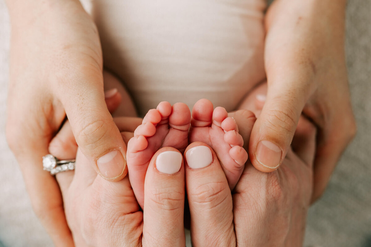 little baby toes with parents hands around them.
