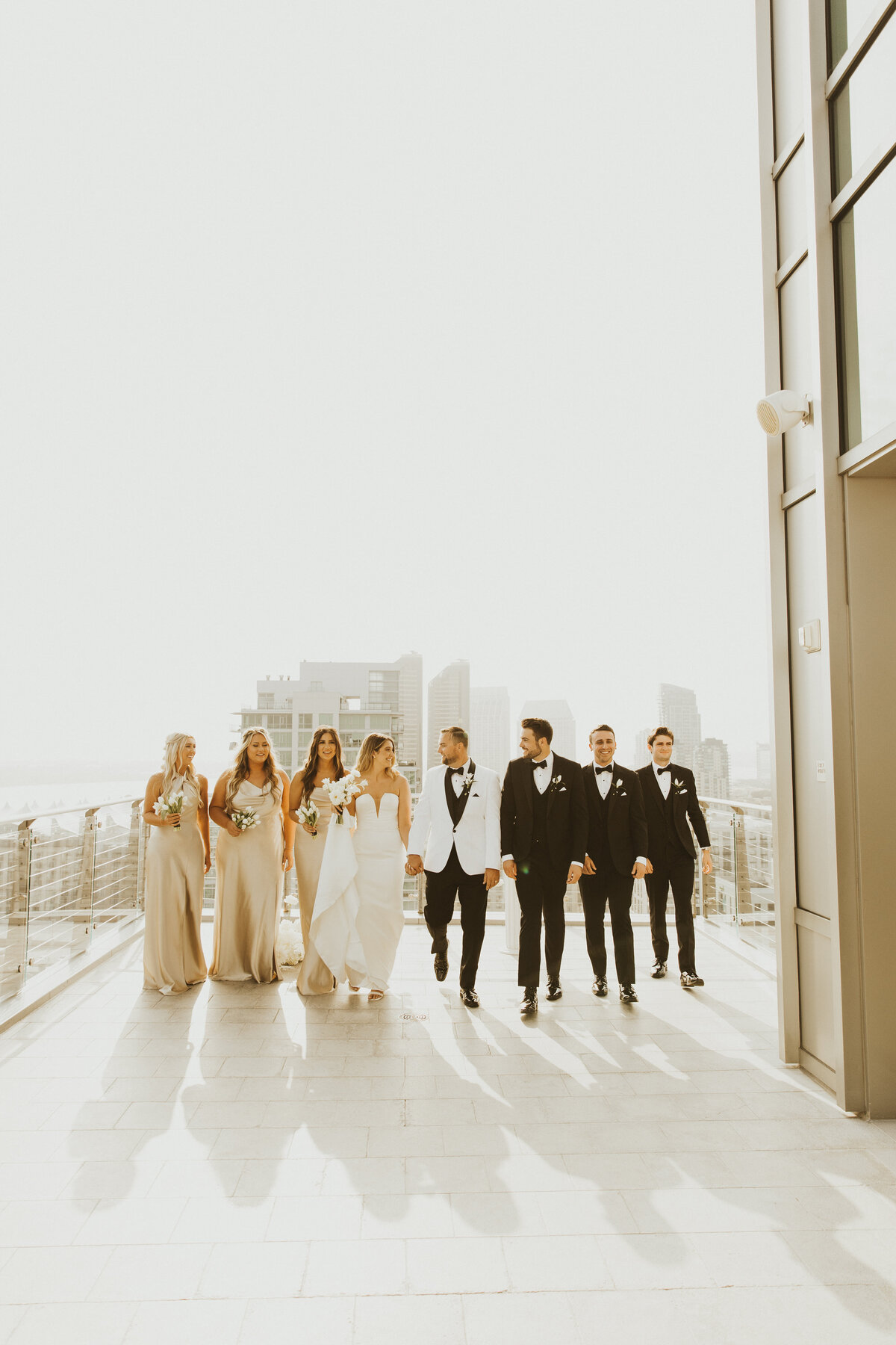 bride and groom walk with their bridal party on a rooftop in san diego