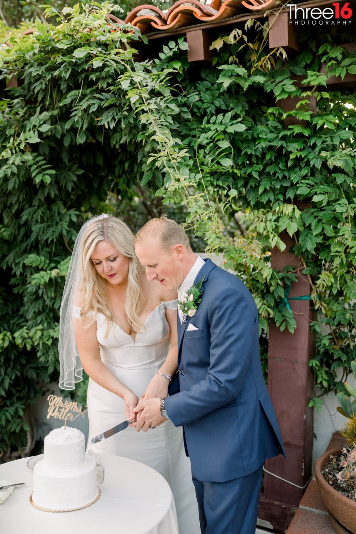 Bride and Groom cut into 2-tiered white wedding cake