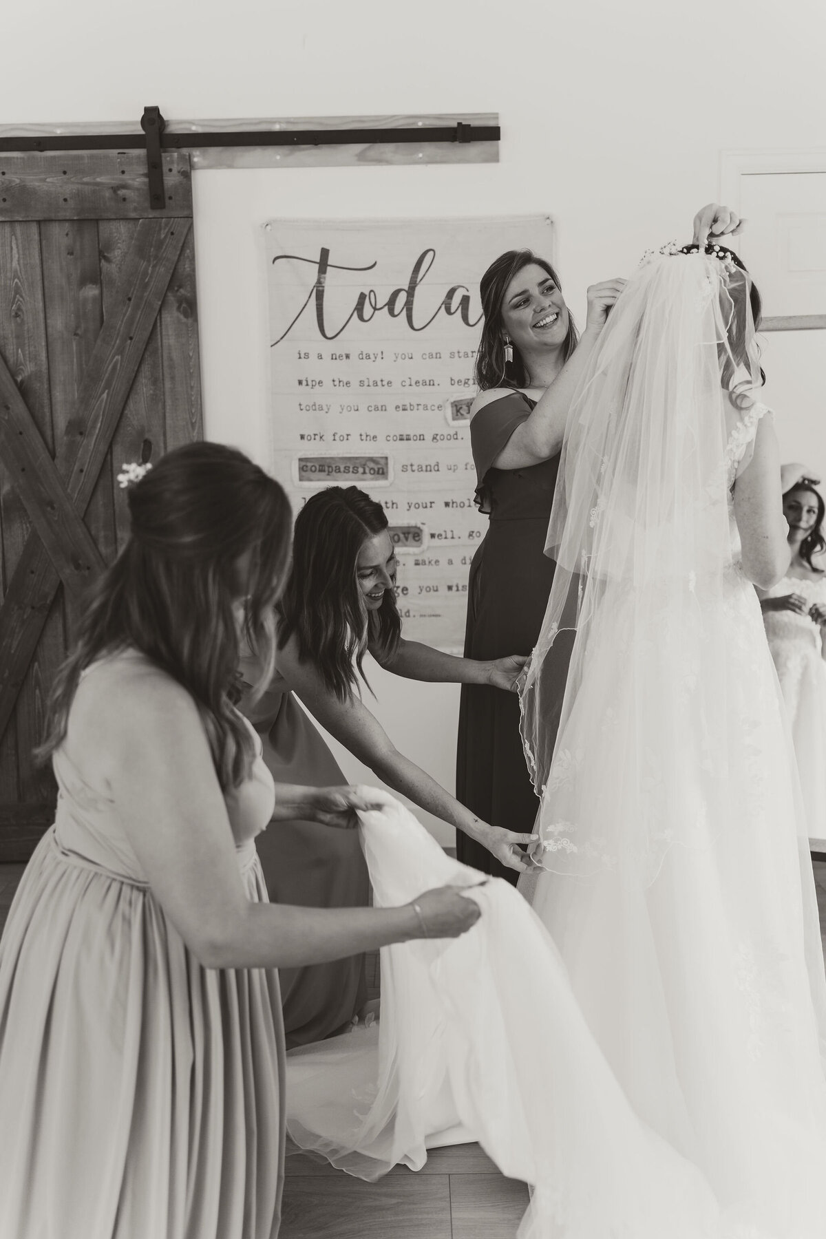 bridesmaids adjust brides Dress while getting ready