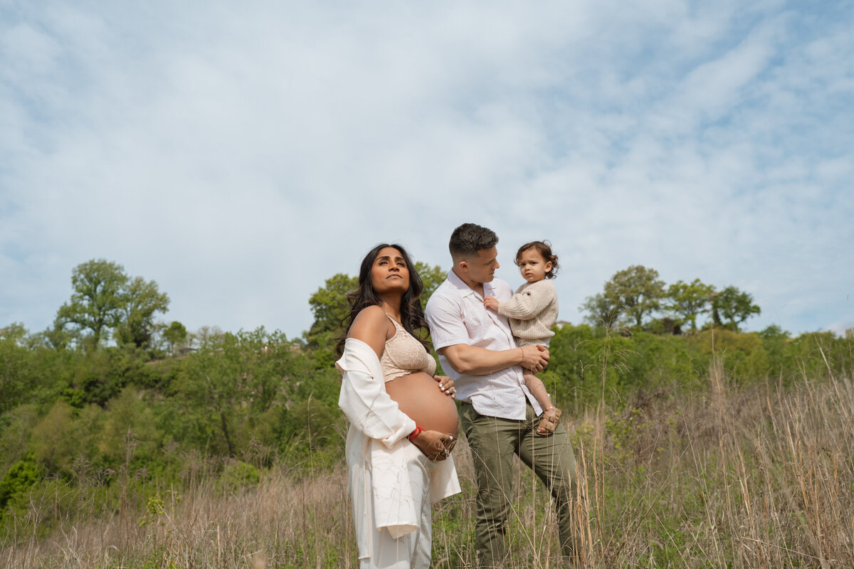 mom standing pregannt with husband and son in field 