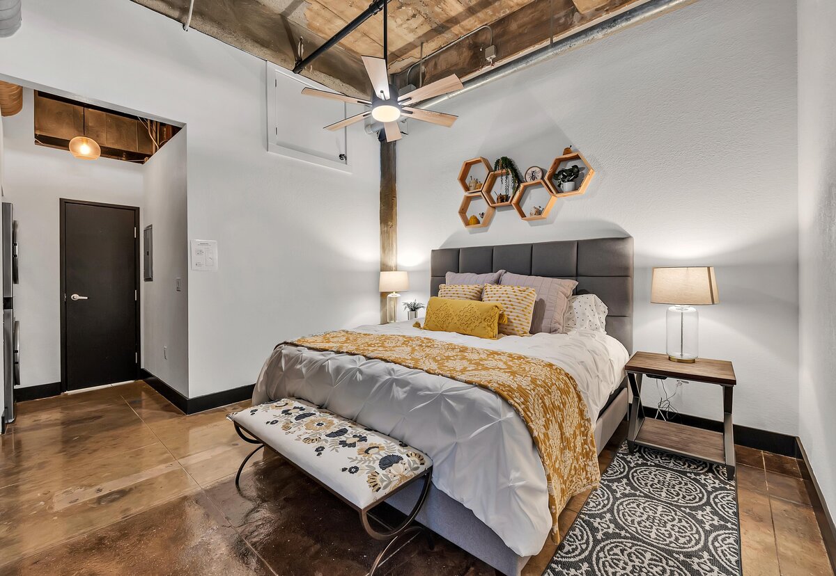 Master bedroom in this Living room with exposed brick in this one-bedroom, one-bathroom vintage condo that sleeps 4 in the historic Behrens building in the heart of the Magnolia Silo District in downtown Waco, TX.