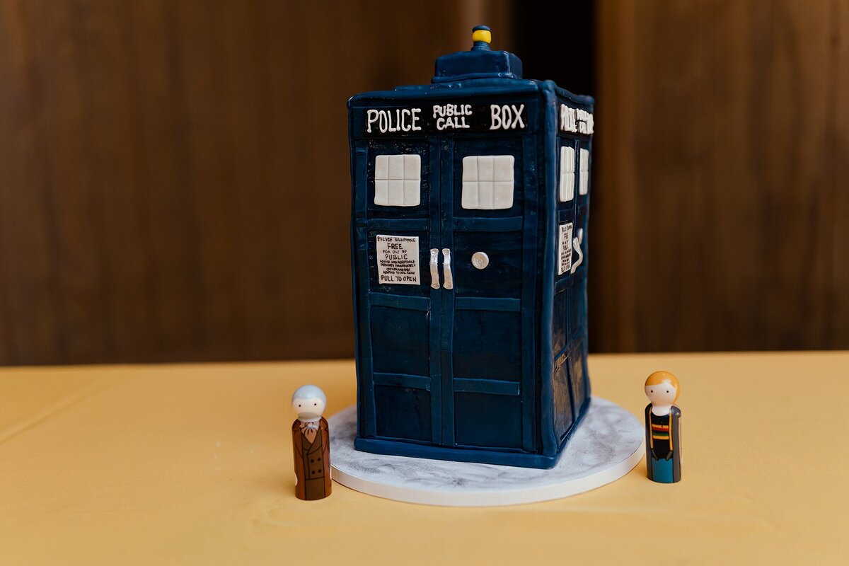 Doctor Who TARDIS groom's cake on a yellow table with two Doctor Who meeples at Loveless Cafe - Loveless Barn