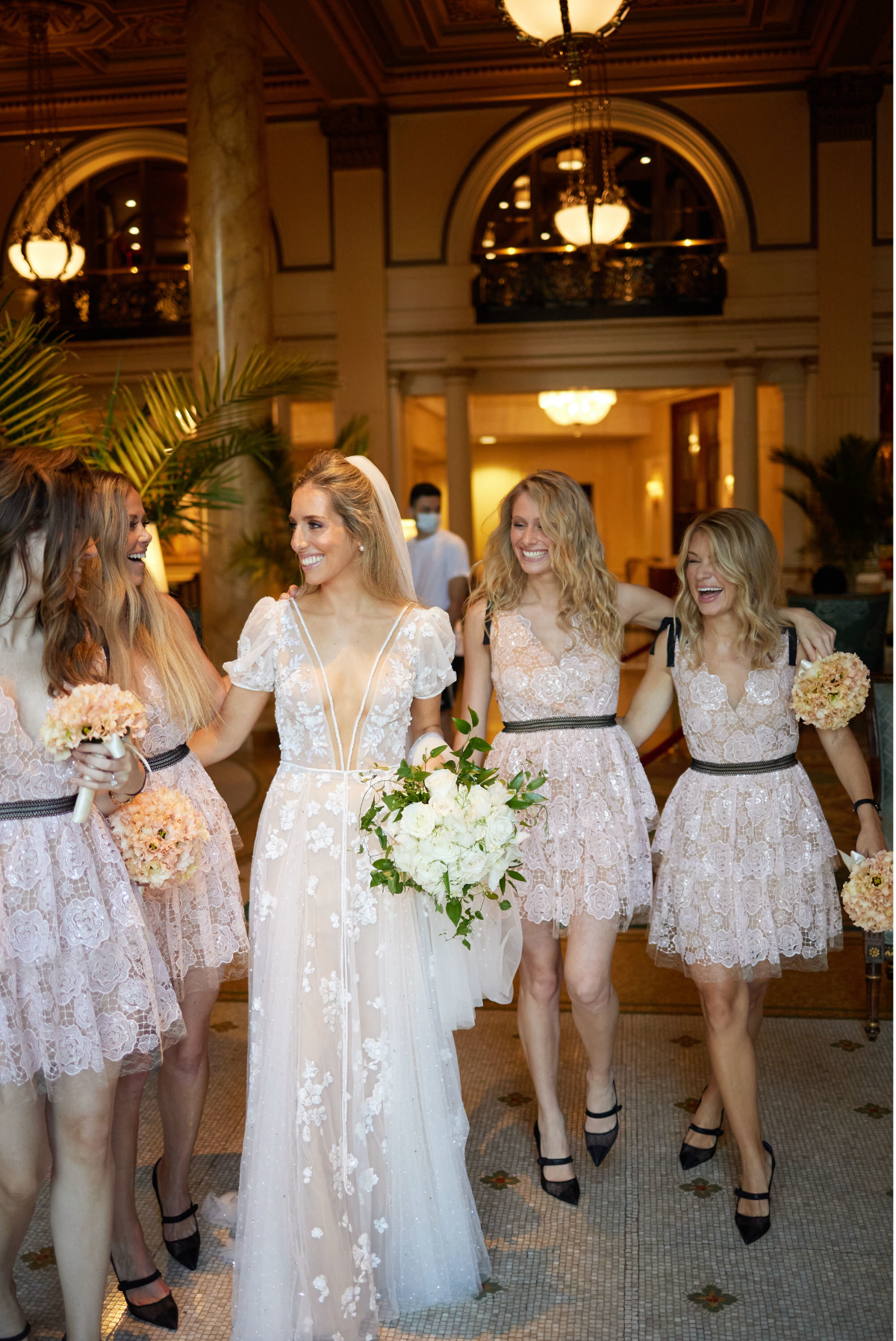 This joyous celebration was captured during a wedding reception at The Willard Intercontinental, one of the top wedding venues and hotels in DC. Photographer Shawn Connell beautifully documented the moment as a smiling woman in a light, frilly dress was lifted on a chair by several men in tuxedos. Her arm raised in delight, she was surrounded by festive décor adorned with flowers and warm lighting. Clayton Films also captured the event as videographers.