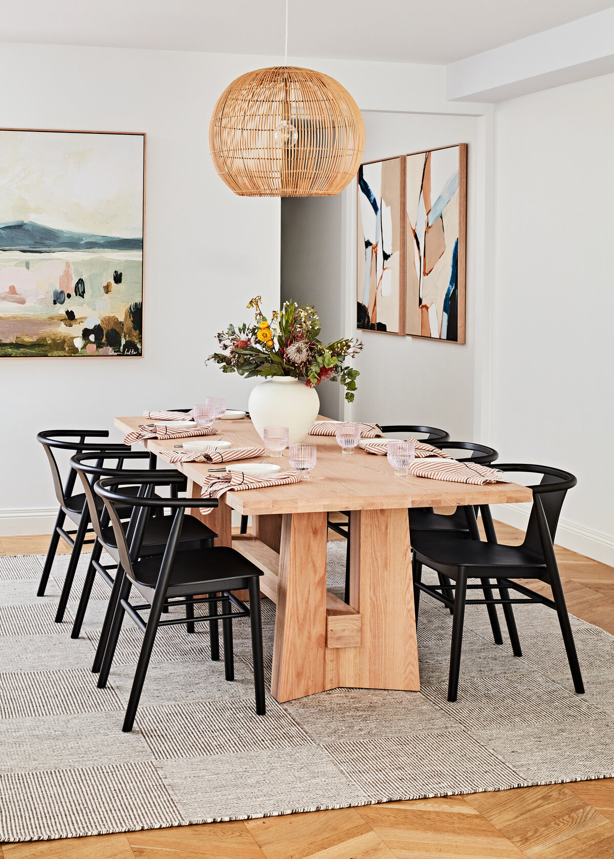 Hampton East dining room with timber table, black dining chairs, and rattan pendant light