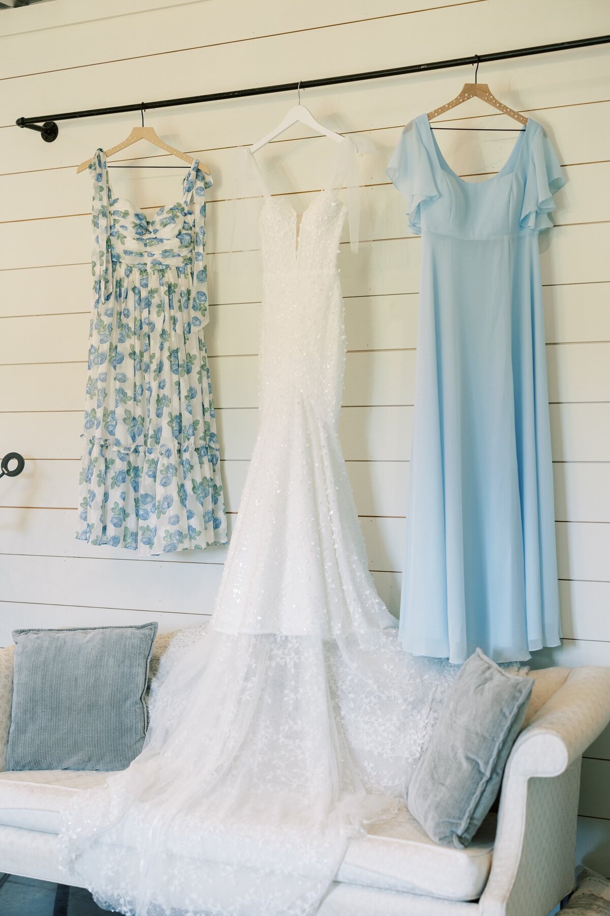 a wedding dress hanging up alongside bridesmaid dresses in a bridal suite