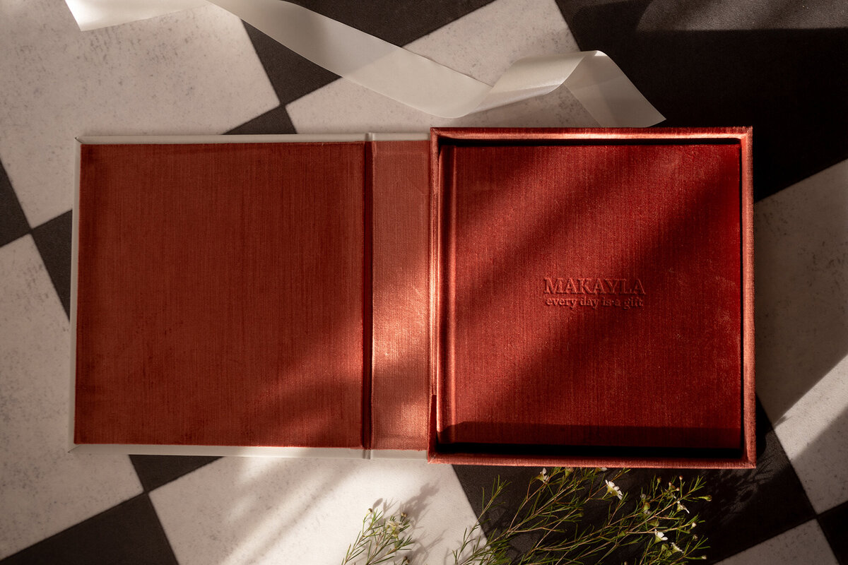 A red heirloom photo album lays open on checker tile