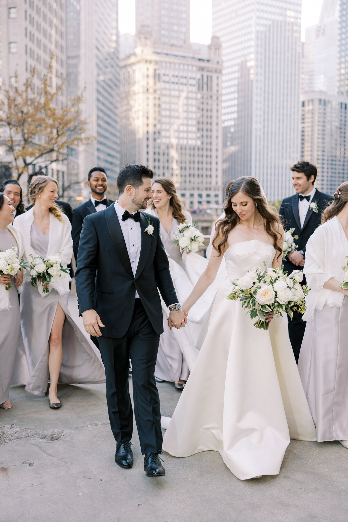 Bride and groom walking with their bridal party in downtown Chicago, planned by Chicago wedding planner Savoir Fête. The Blackstone Hotel wedding showcases urban elegance.
