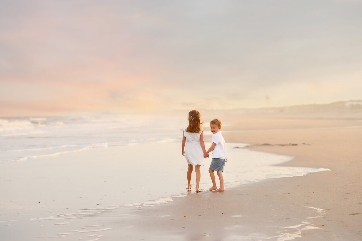 Siblings walk hand in hand along the beach during Family Pictures on Isle of Palms. 