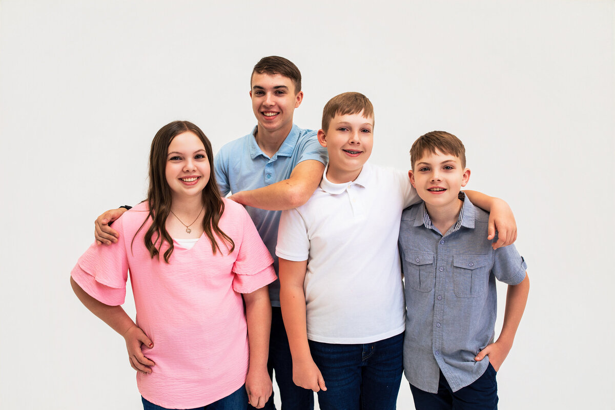 For siblings embrace against a solid white studio background in the Pittsburgh photography studio