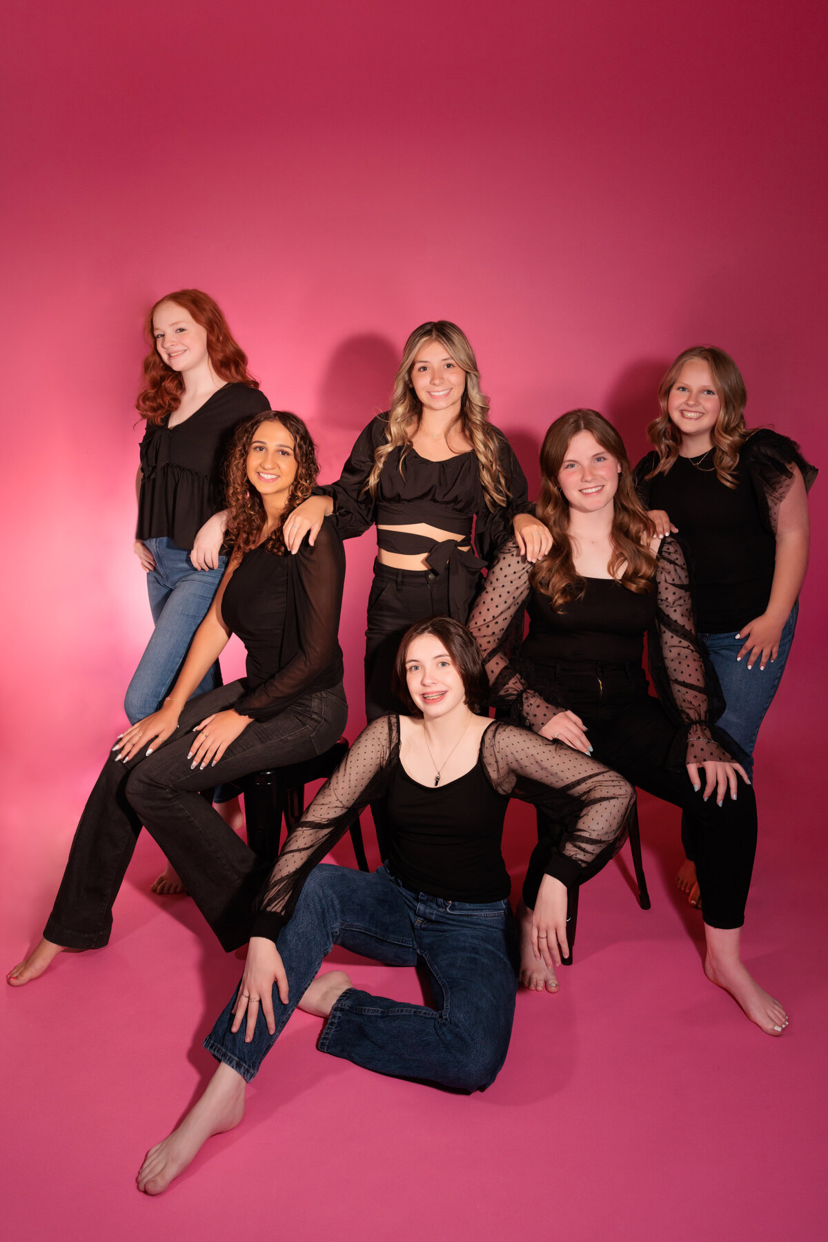 High School Seniors beautiful group of ladies wearing black with a pink backdrop.