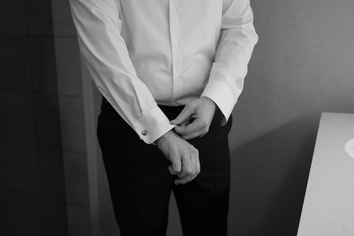 A close up of a man straightening his shirt cuffs.