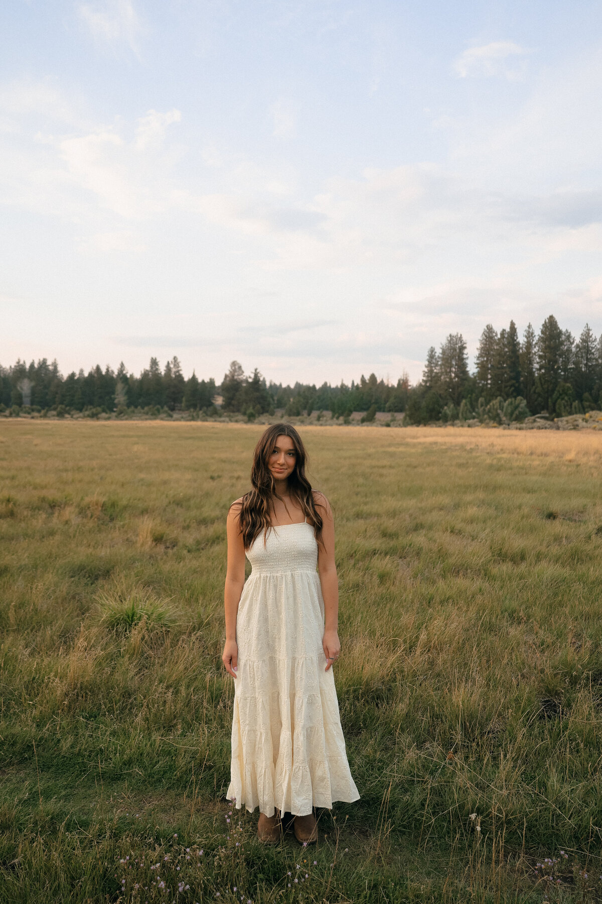 Senior Portrait of Girl Standing in Open Field Wearing Cream Dress at Sunset in Oregon Countryside