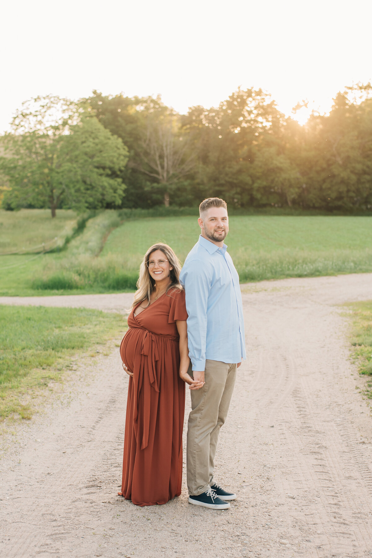 Expecting mother and father, standing back to back on dirt road