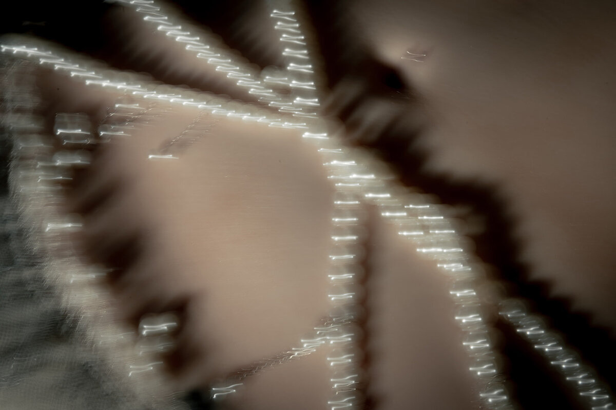 An editorial blurry photo of pearls across a brides tummy.