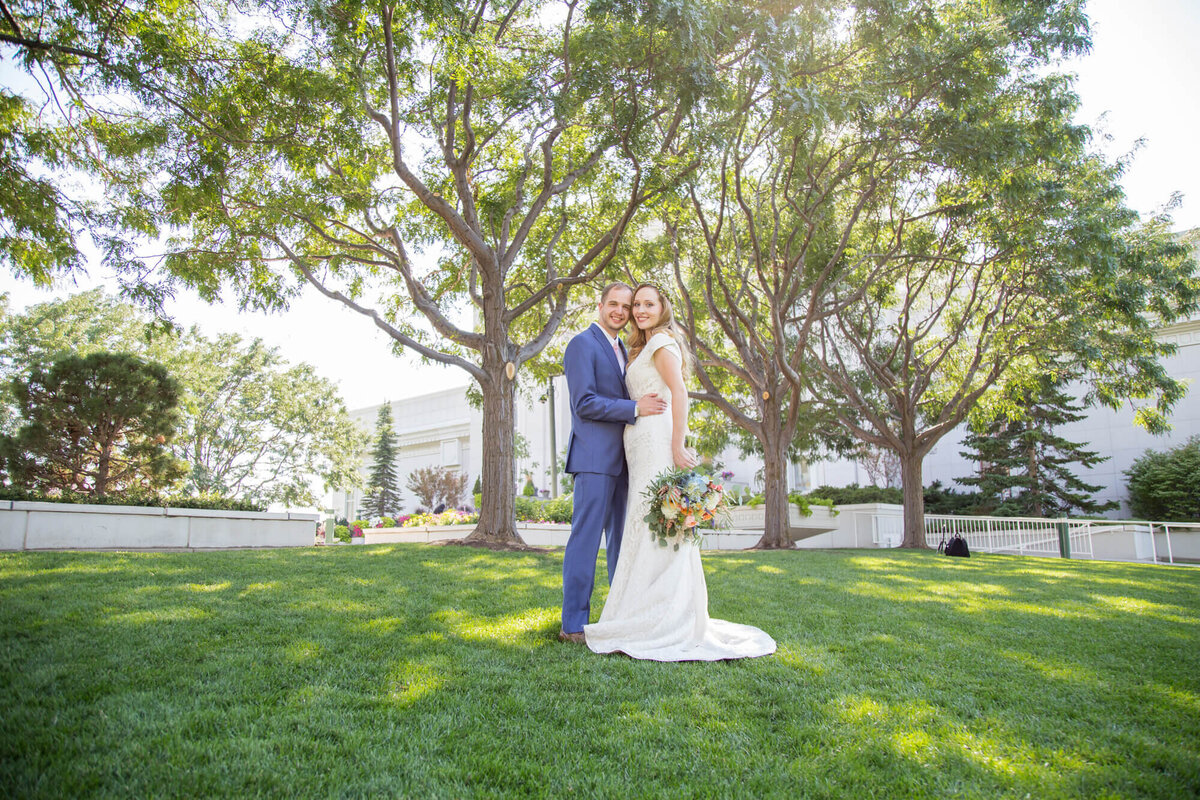 wedding couple standing in front of draper utah lds temple on bright wedding day