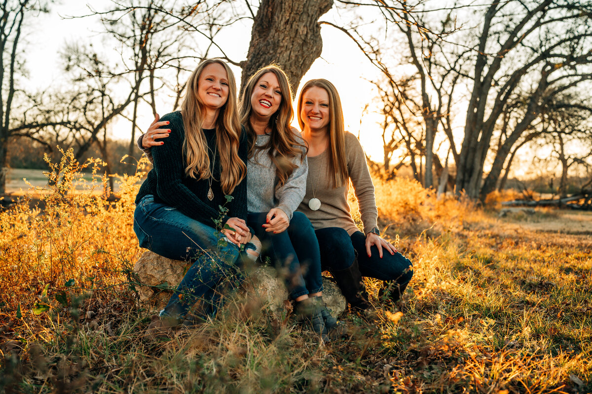 Family sitting together in a field during golden hour — joyful Fort Worth family photography by Poppy + Blue Photography