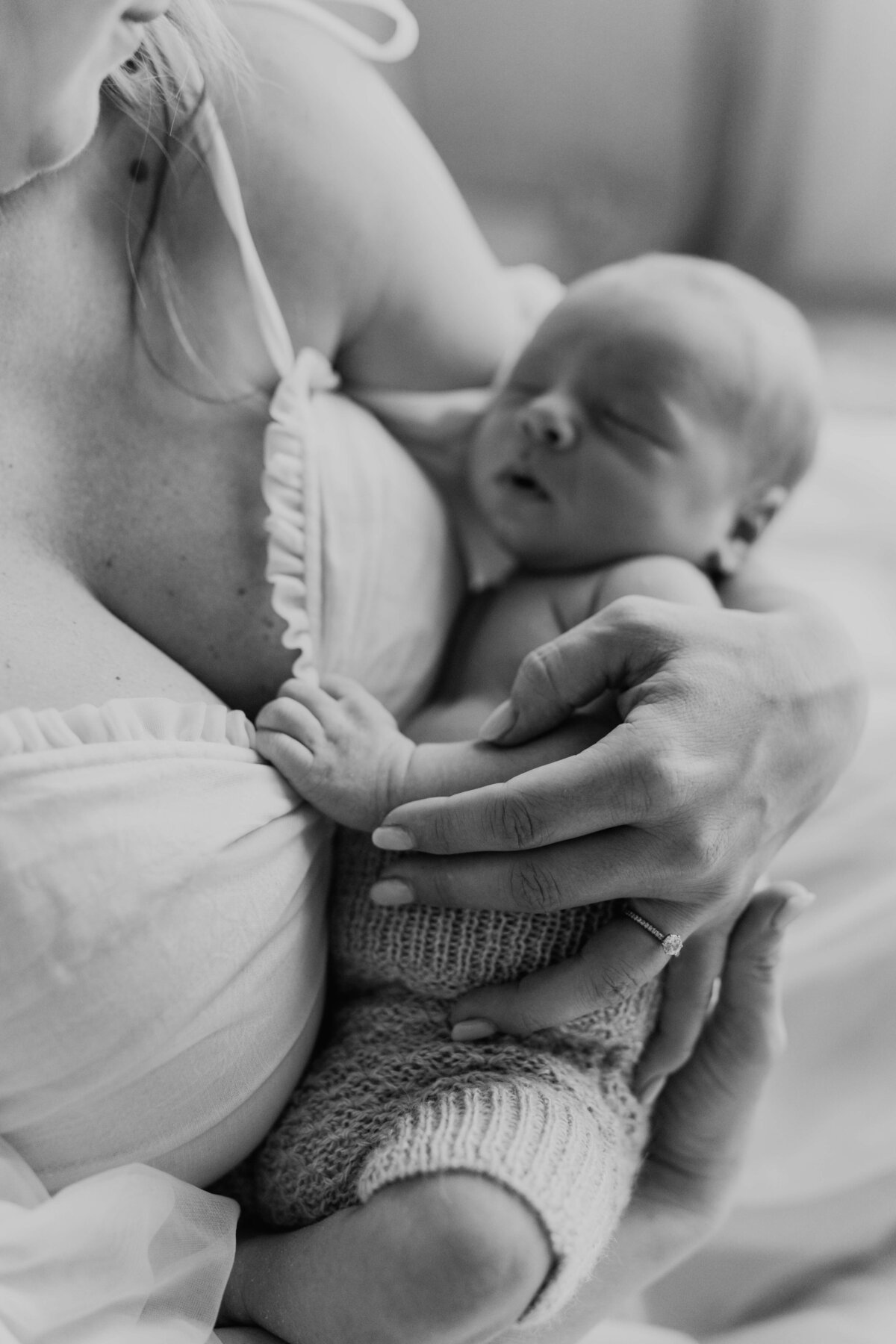 newborn boy holds on to his mom's dress as he sleeps