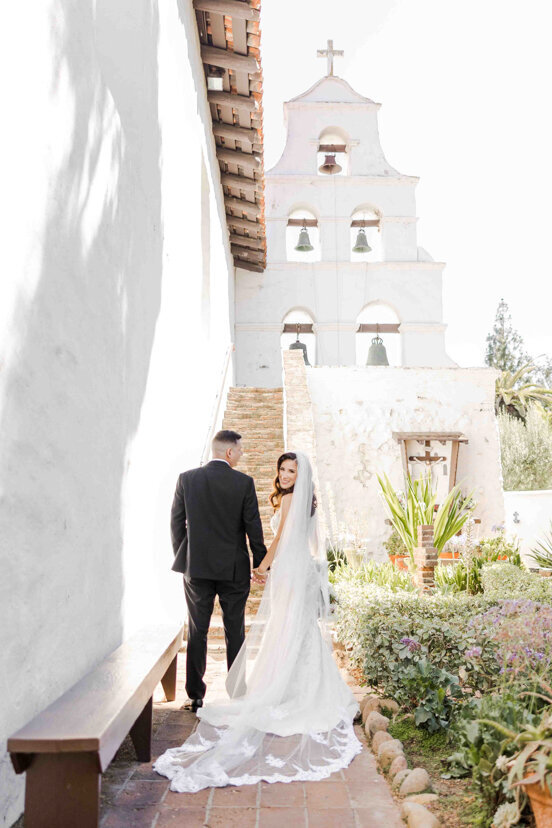 bride-and-groom-under-bell-tower-at-mission-san-diego-de-alcala-wedding