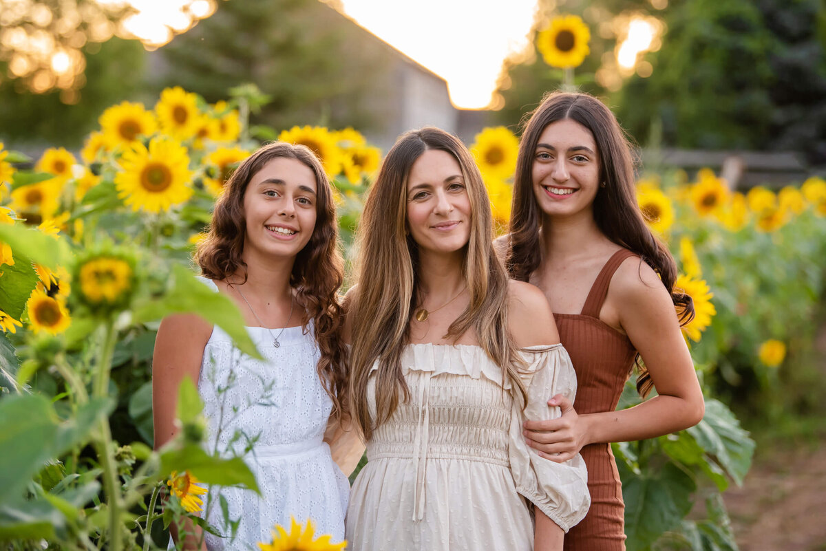 mom with her two teenage girls in a sunflower field for their Burlington family photographer session 