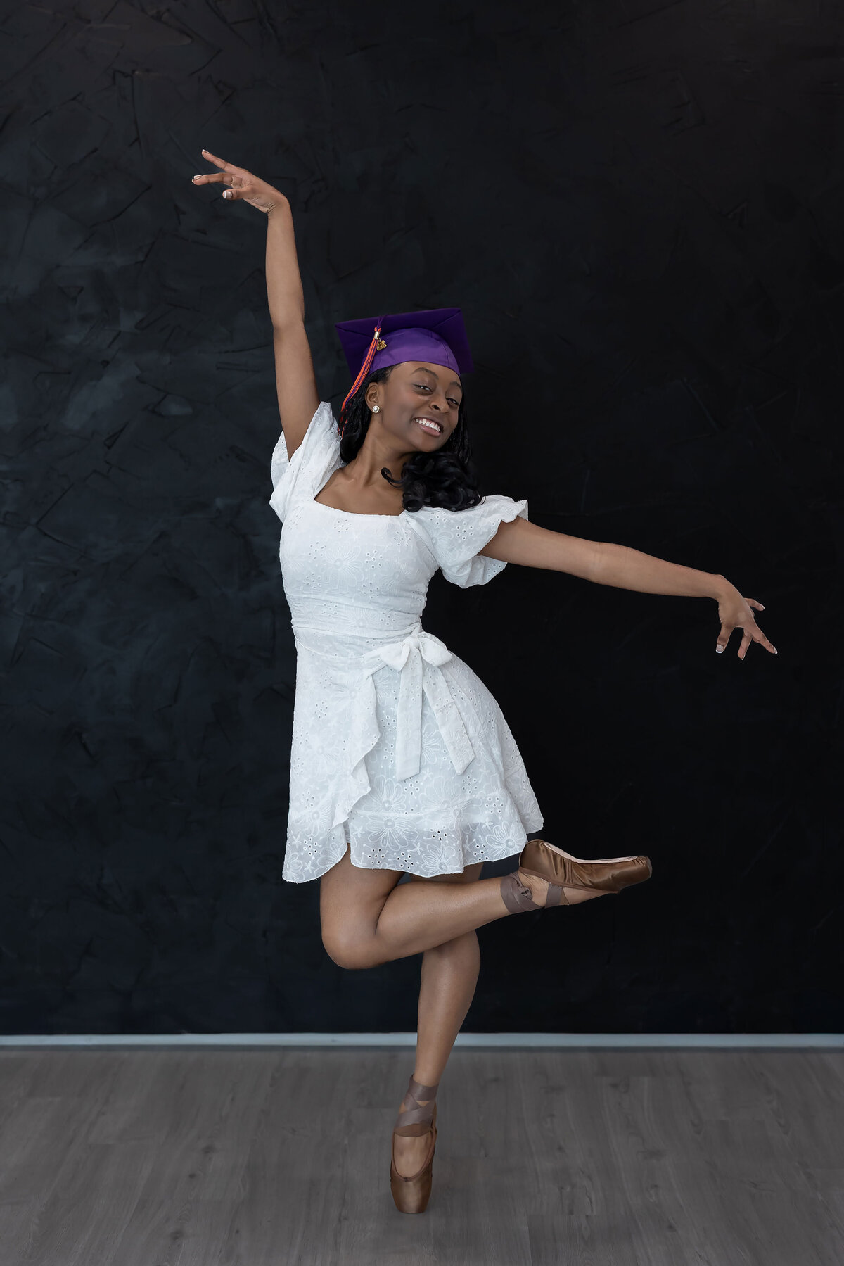 Creative senior photo of a graduated dancer striking a unique pose in a Dallas studio, part of a standout Senior Photography Portfolio.