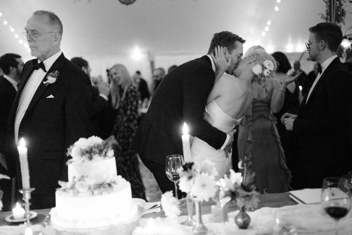 The bride and groom are kissing in the middle of the dance floor in Foxfire Mountain House, New York. Wedding Image by Jenny Fu Studio