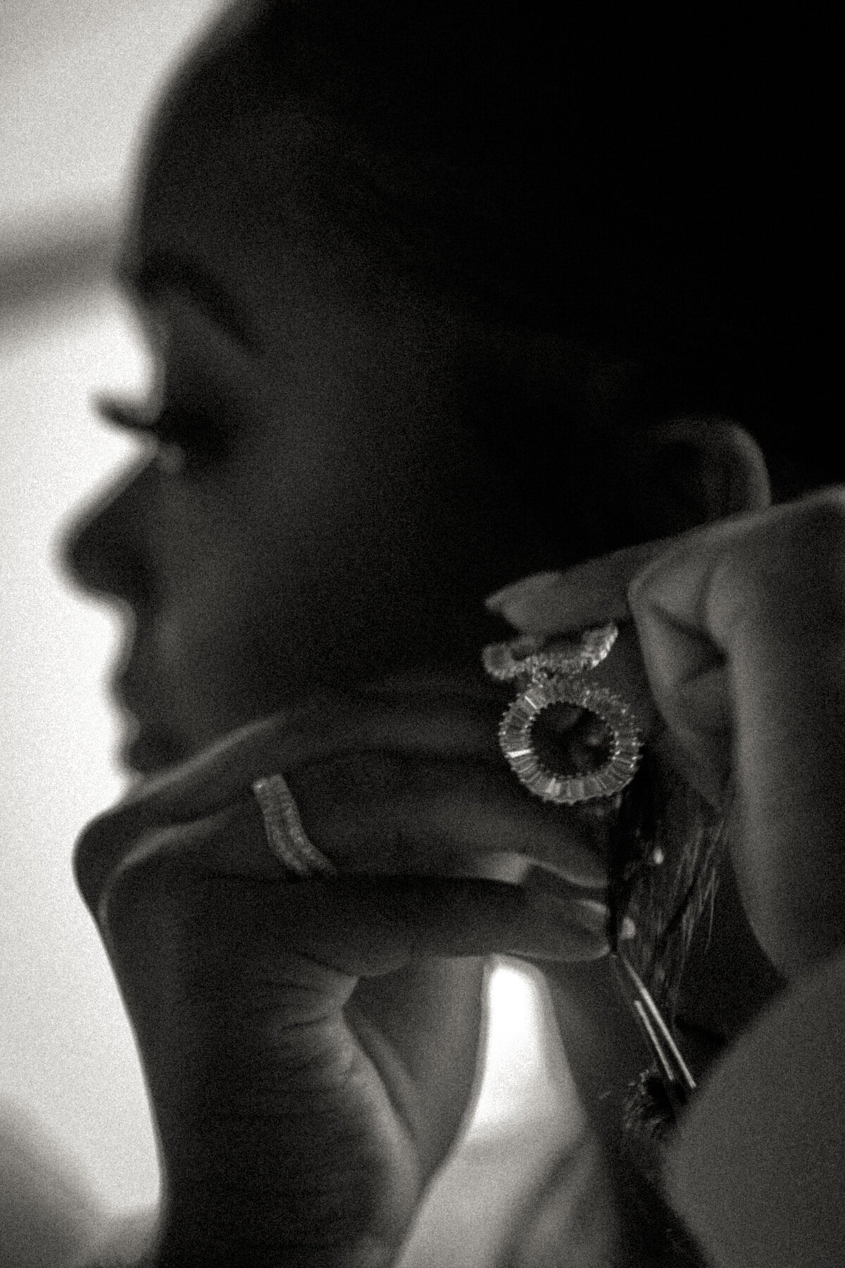 A classic black-and-white portrait capturing the bride adjusting her earring, highlighting a moment of calm at Brake and Clutch Warehouse in Dallas.