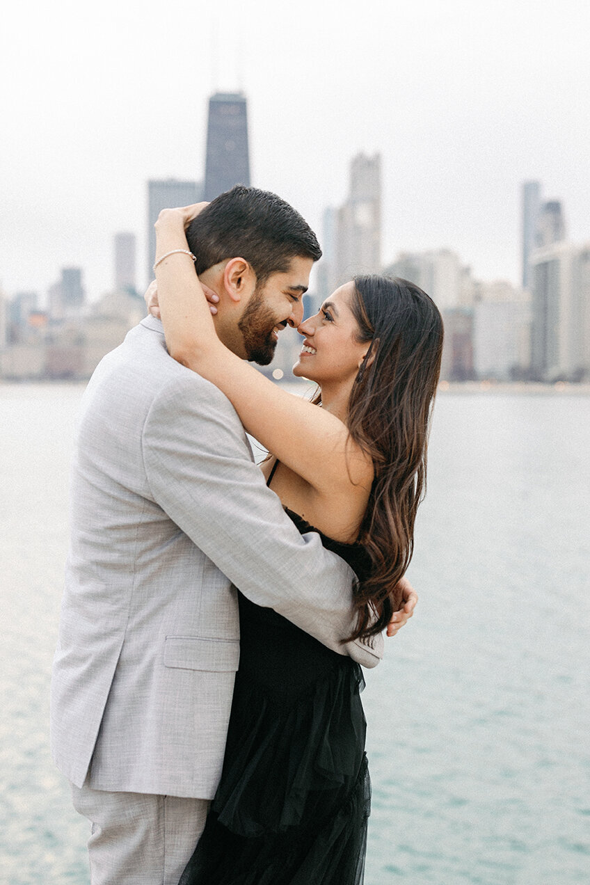 Couple in formal attire pose for engagement photo at North Avenue Beach in Chicago