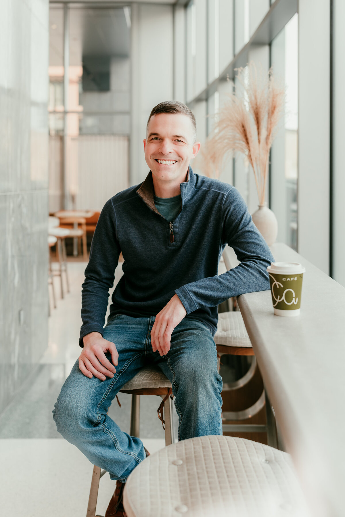 Man seated in a contemporary coffee shop, exuding confidence and authenticity for his online dating profile.