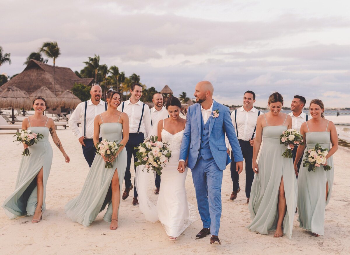 Bride groom and bridal party walking on beach at wedding in Riviera Maya