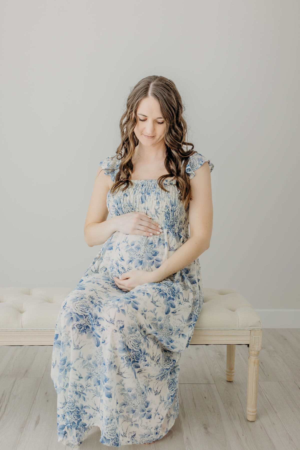 Happy pregnant mom in blue dress sitting on bench
