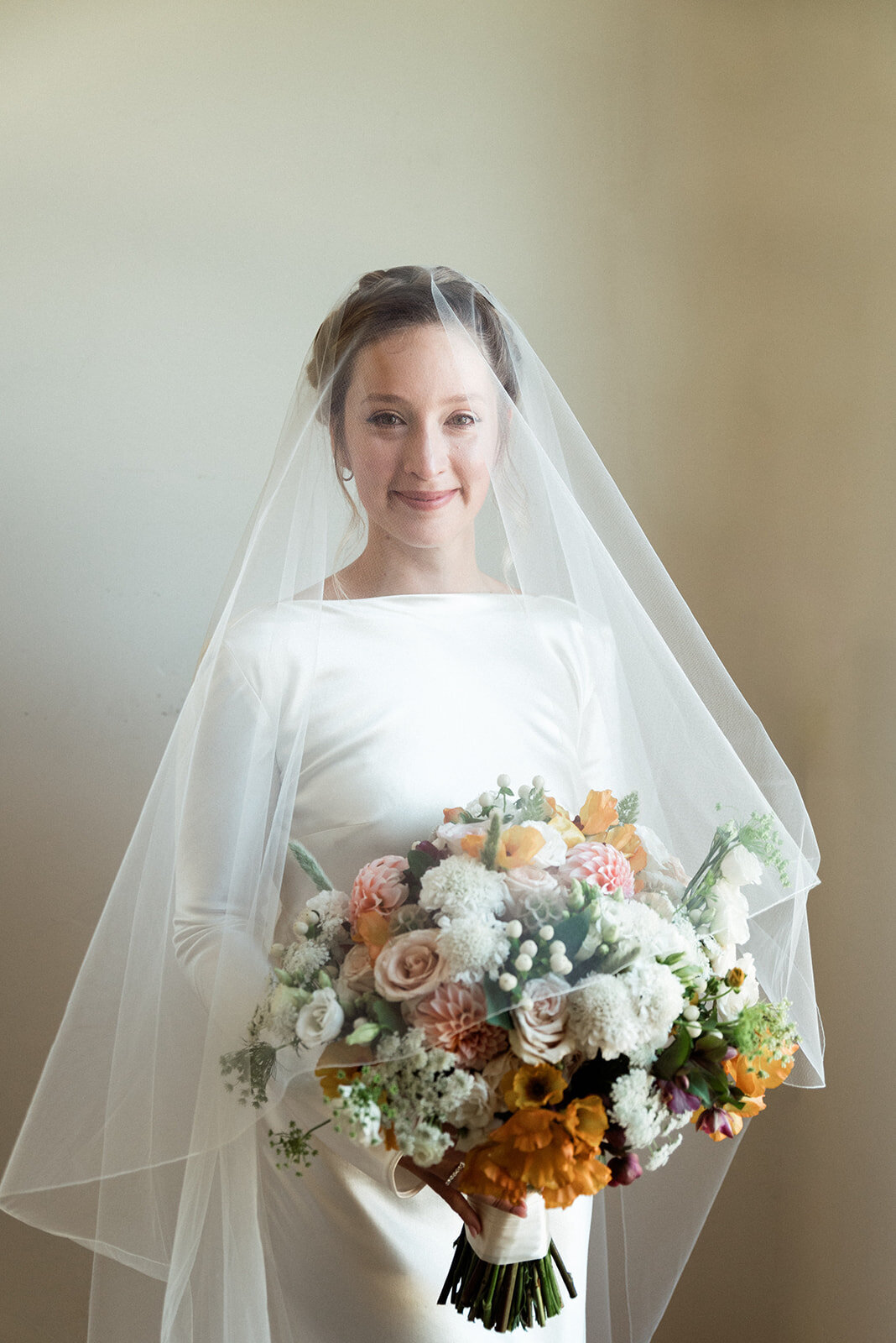 Bride holding a bouquet of wedding flowers and smiling at the camera.