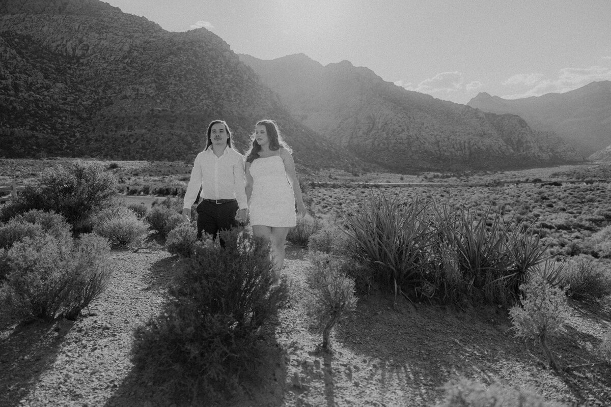 Engaged couple walking with mountains in the background in Nevada
