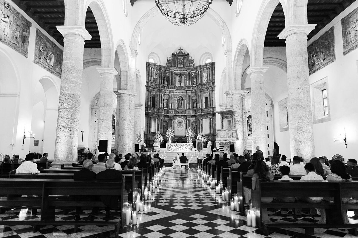 A breathtaking black-and-white shot of Victoria and Daniel’s Cartagena Colombia wedding ceremony in a historic cathedral, with candlelit aisles and grand architecture.