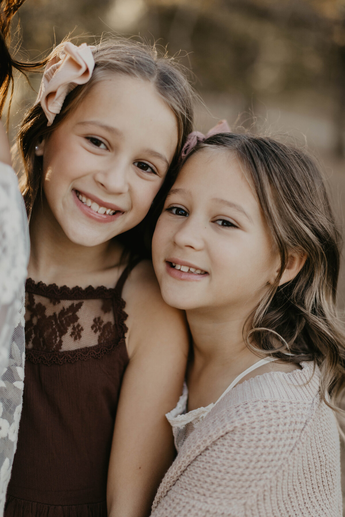 Two younger sisters with cheeks close to one another. 