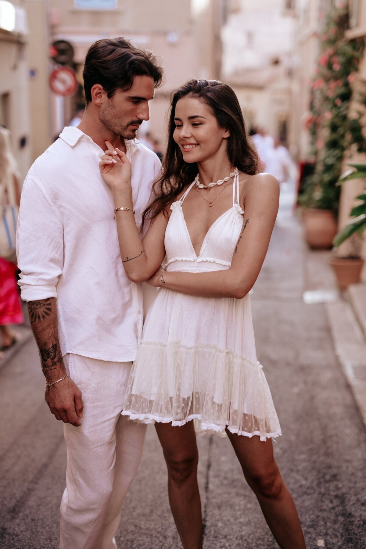 Man looking loving at his fiance while she looks off and smiles.